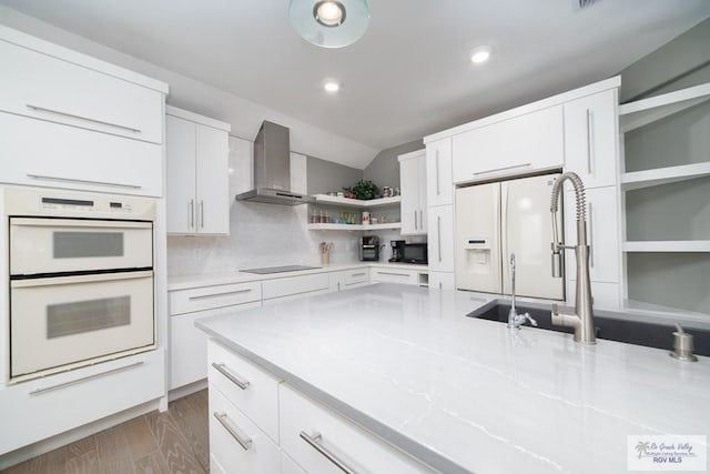 kitchen featuring white appliances, tasteful backsplash, wall chimney exhaust hood, white cabinetry, and open shelves