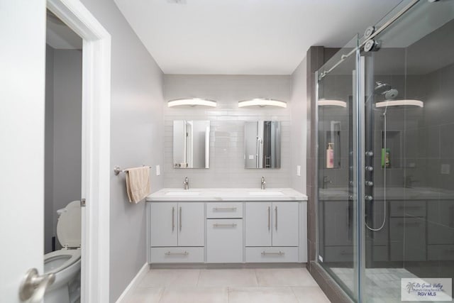 full bath with double vanity, a stall shower, a sink, and tile patterned floors