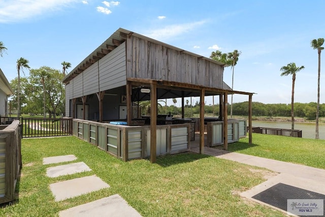 exterior space featuring a lawn, a water view, and an outdoor kitchen