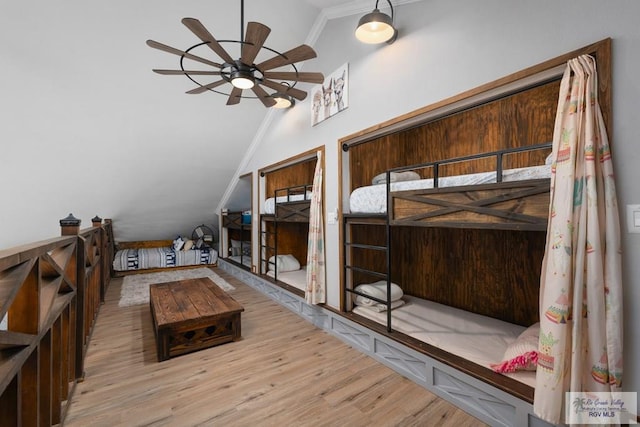 bedroom with light hardwood / wood-style floors, lofted ceiling, and crown molding