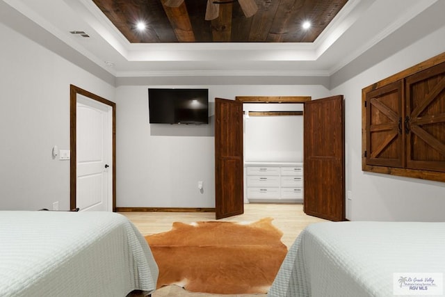 bedroom with a raised ceiling, light hardwood / wood-style floors, and ornamental molding