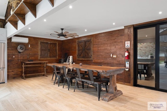 dining area featuring an AC wall unit, wooden walls, ceiling fan, and light hardwood / wood-style floors