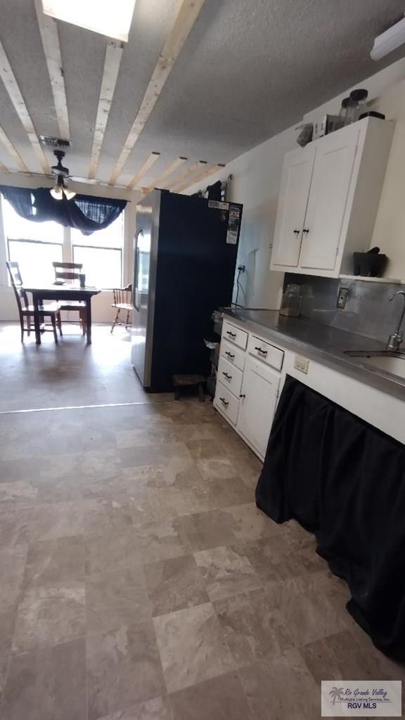 515 Honeydale Rd, Brownsville, TX 78520 - kitchen with freestanding refrigerator, white cabinetry, and ceiling fan