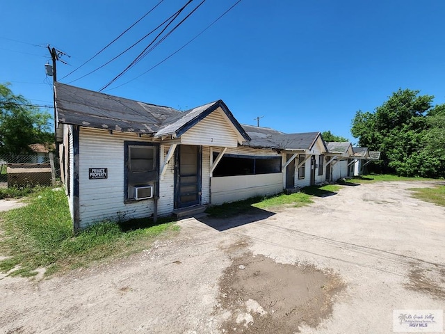 view of front of house featuring dirt driveway, fence, and cooling unit