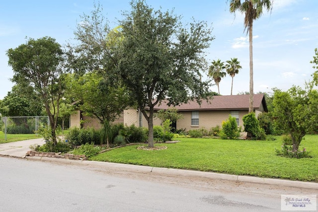 view of front of home featuring brick siding, a front yard, and fence