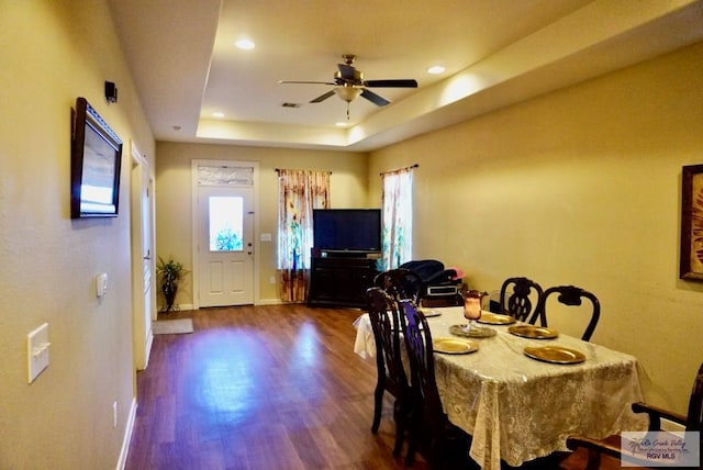 dining area with dark hardwood / wood-style floors, ceiling fan, and a tray ceiling