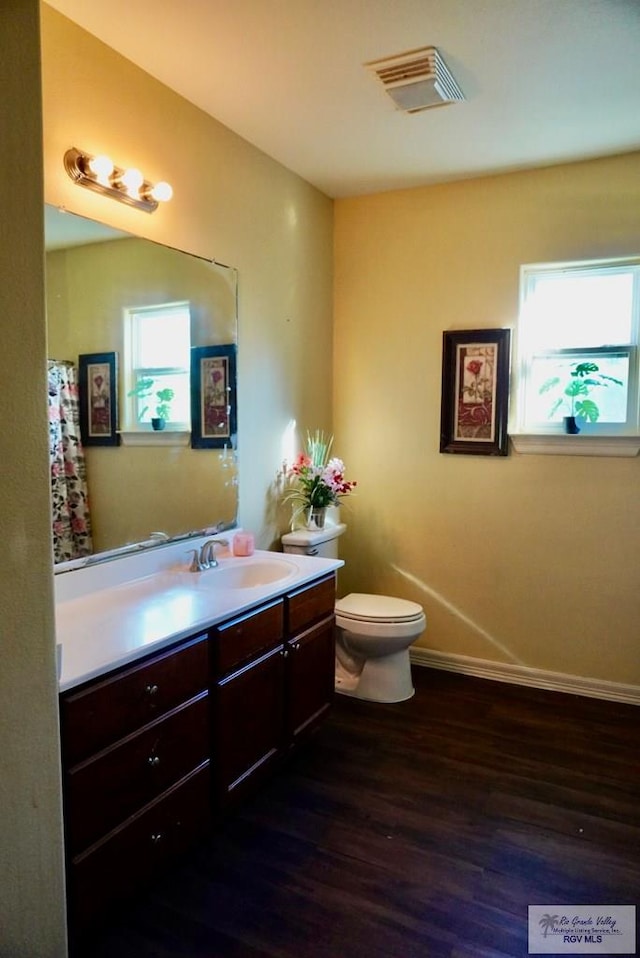 bathroom featuring hardwood / wood-style flooring, plenty of natural light, toilet, and vanity