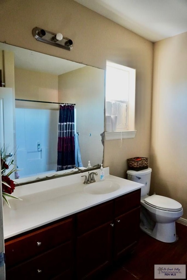 bathroom featuring a shower with curtain, vanity, hardwood / wood-style flooring, and toilet