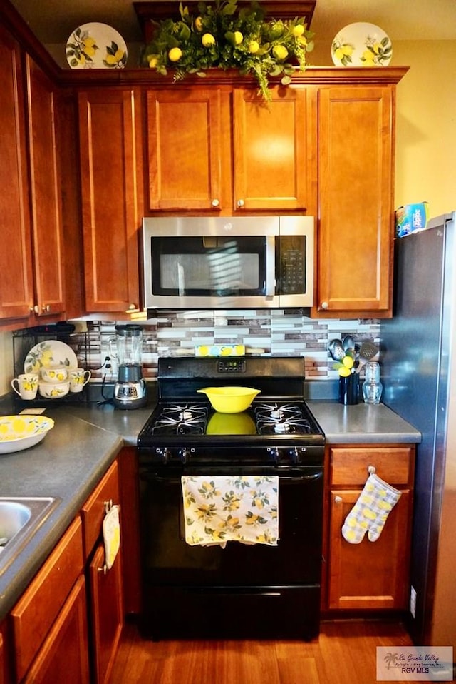 kitchen with light wood-type flooring, stainless steel appliances, and tasteful backsplash