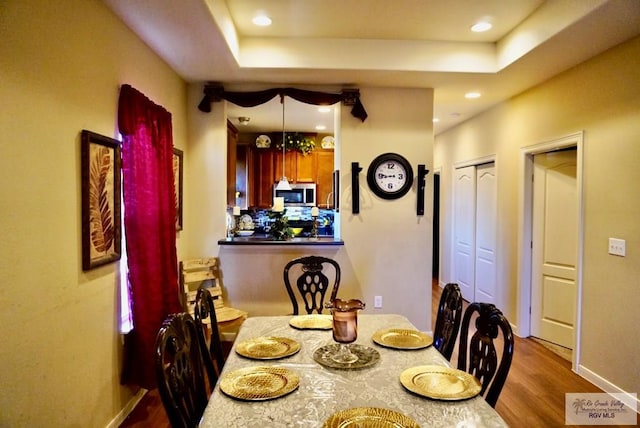 dining area featuring hardwood / wood-style flooring and a tray ceiling