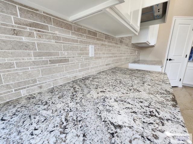 interior space featuring white cabinets, light stone counters, and tasteful backsplash