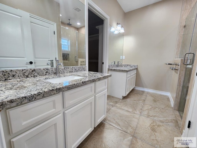 full bath with a shower stall, two vanities, baseboards, and a sink