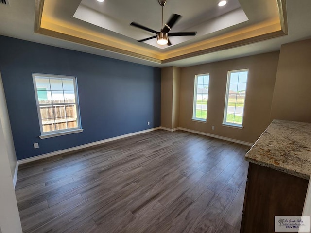 empty room with ceiling fan, baseboards, a tray ceiling, recessed lighting, and dark wood-style floors