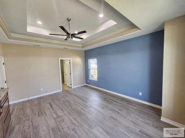 interior space featuring visible vents, baseboards, light wood-type flooring, a raised ceiling, and a ceiling fan