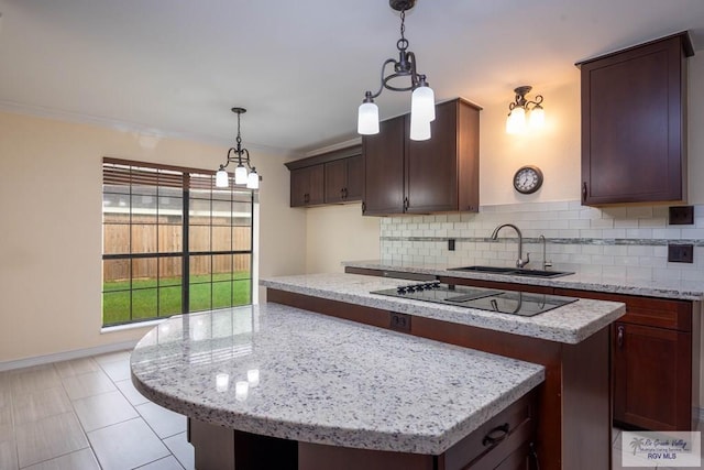 kitchen featuring backsplash, light stone counters, dark brown cabinetry, and sink