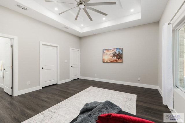 bedroom with dark hardwood / wood-style flooring, a tray ceiling, and ceiling fan