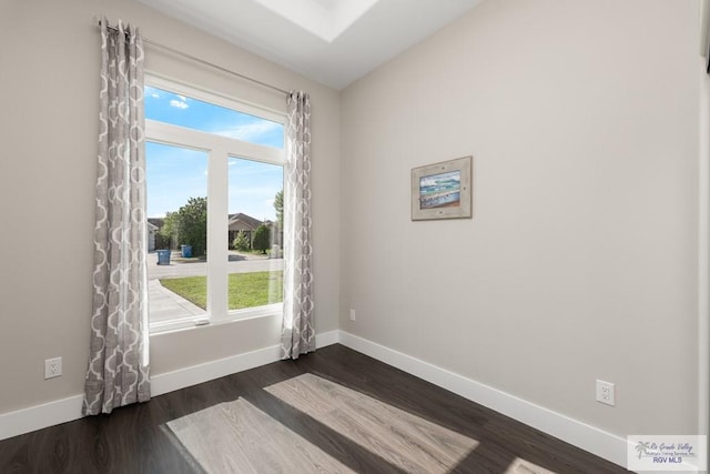 spare room featuring dark hardwood / wood-style floors and vaulted ceiling