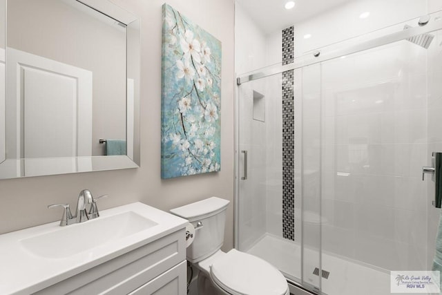 bathroom featuring vanity, toilet, and a shower with shower door