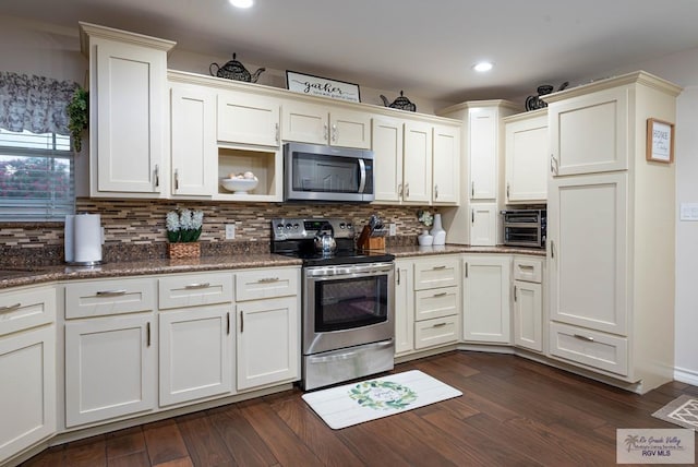 kitchen featuring dark stone countertops, tasteful backsplash, stainless steel appliances, and dark wood-type flooring