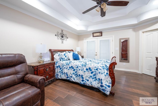 bedroom with a raised ceiling, crown molding, dark wood-type flooring, and ceiling fan with notable chandelier