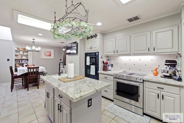 105 E Austin Ave, Harlingen, TX 78550 - kitchen with stainless steel range with electric stovetop, a chandelier, light tile patterned floors, a center island with sink, and decorative backsplash