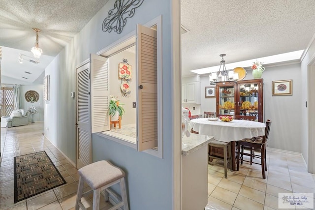 105 E Austin Ave, Harlingen, TX 78550 - hall with light tile patterned floors, a chandelier, a textured ceiling, and lofted ceiling