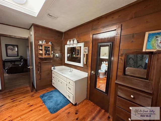 bathroom featuring hardwood / wood-style floors, vanity, and wood walls