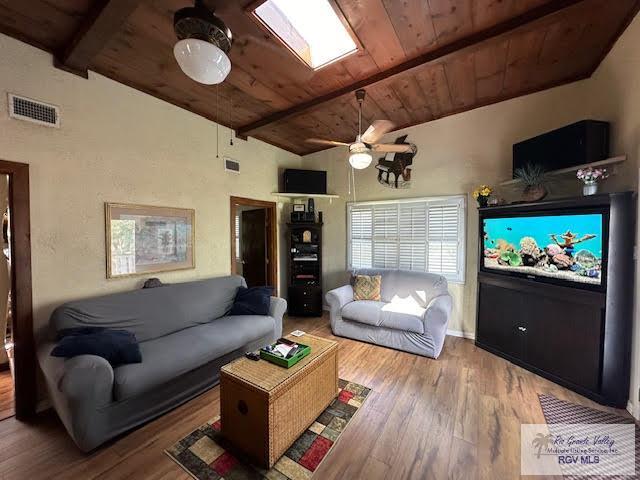 living room with vaulted ceiling with beams, hardwood / wood-style flooring, ceiling fan, and wooden ceiling