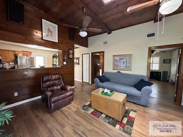 living room featuring beam ceiling, hardwood / wood-style floors, and high vaulted ceiling