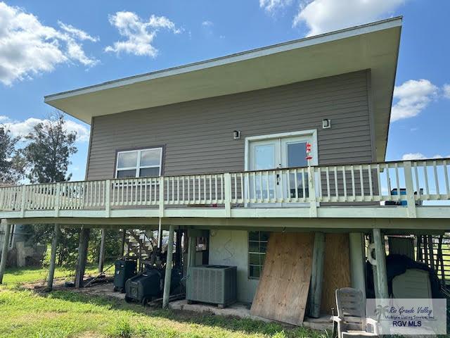 back of property with a lawn, a wooden deck, and central AC