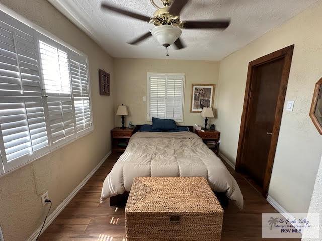 bedroom with multiple windows, ceiling fan, a textured ceiling, and hardwood / wood-style flooring