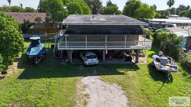 back of house with a carport, a wooden deck, and a lawn