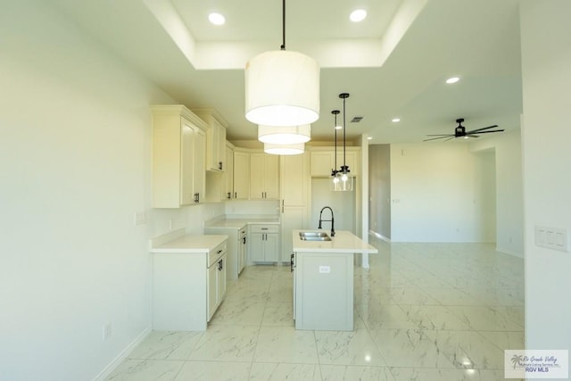 kitchen with pendant lighting, white cabinetry, sink, a kitchen island with sink, and ceiling fan