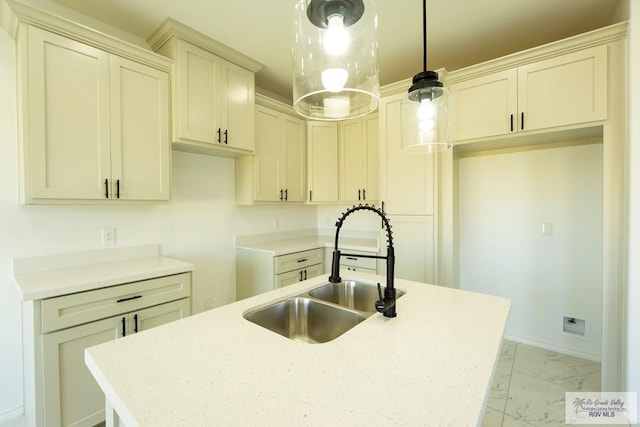 kitchen featuring decorative light fixtures, a kitchen island with sink, and sink