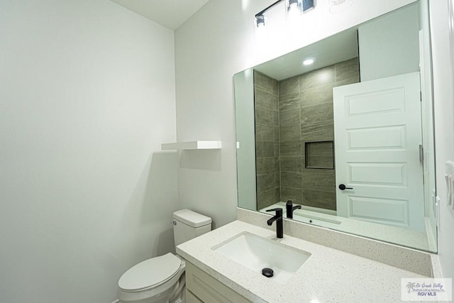 bathroom featuring vanity, toilet, and a tile shower