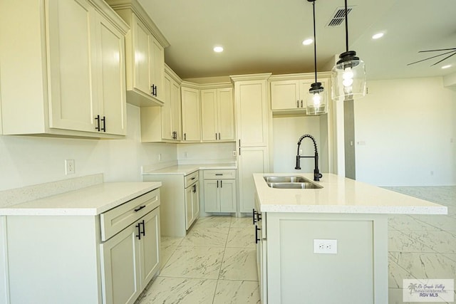 kitchen featuring sink, decorative light fixtures, and a kitchen island with sink