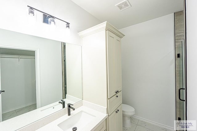 bathroom featuring a shower with door, vanity, and toilet