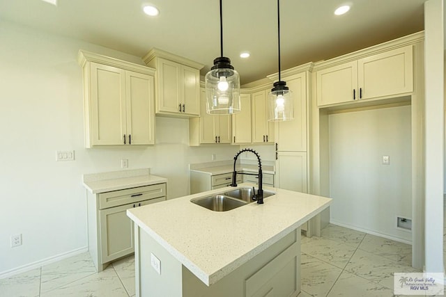 kitchen with an island with sink, light stone countertops, sink, and decorative light fixtures