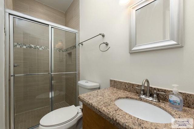 bathroom featuring vanity, toilet, and a shower with door