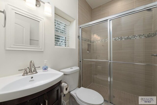 bathroom with vanity, toilet, and a shower with door