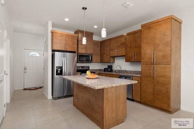 kitchen featuring a center island, sink, stainless steel appliances, decorative light fixtures, and light tile patterned flooring