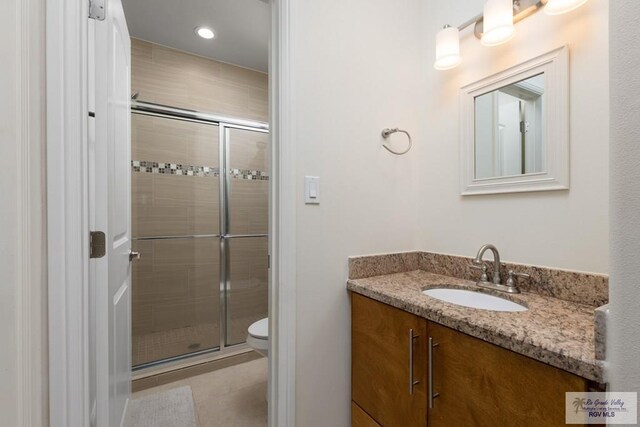 bathroom featuring vanity, toilet, and a shower with shower door