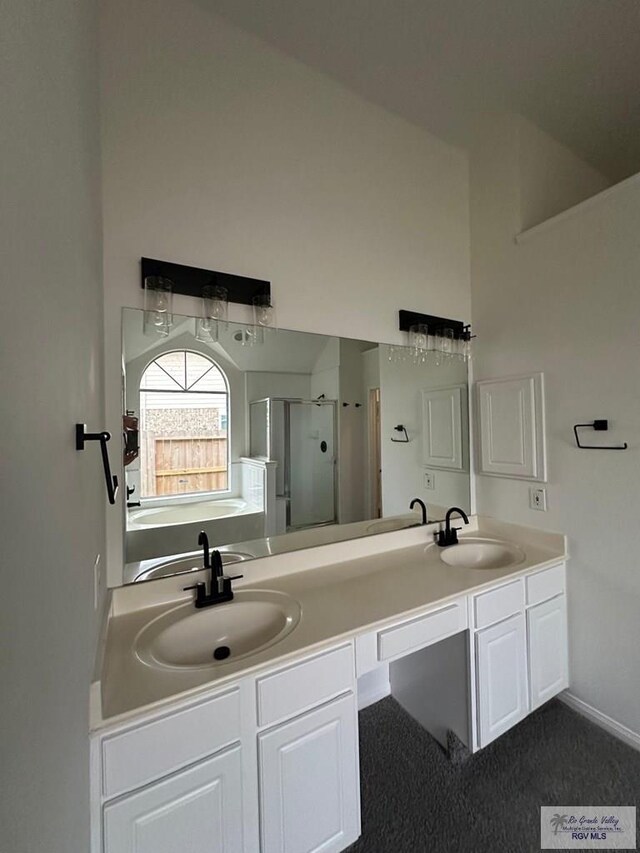 full bath featuring a stall shower, double vanity, a bath, and baseboards