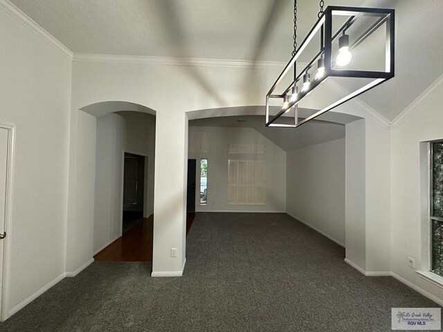 carpeted empty room featuring arched walkways, crown molding, baseboards, and vaulted ceiling