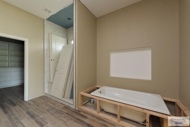 bathroom featuring wood-type flooring and a tub to relax in