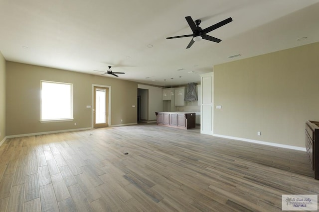 unfurnished living room with light hardwood / wood-style flooring and ceiling fan