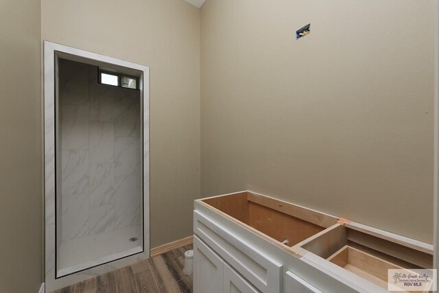 interior space with wood-type flooring, toilet, and walk in shower