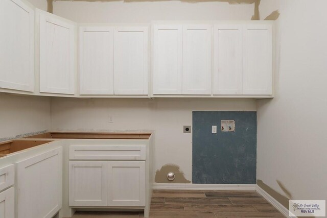 laundry area with electric dryer hookup, cabinets, and dark wood-type flooring