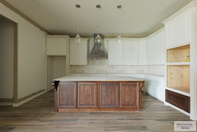 kitchen featuring white cabinets, dark hardwood / wood-style floors, a kitchen island, and hanging light fixtures