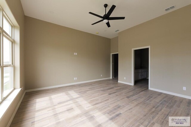 spare room featuring ceiling fan, light hardwood / wood-style floors, and a towering ceiling